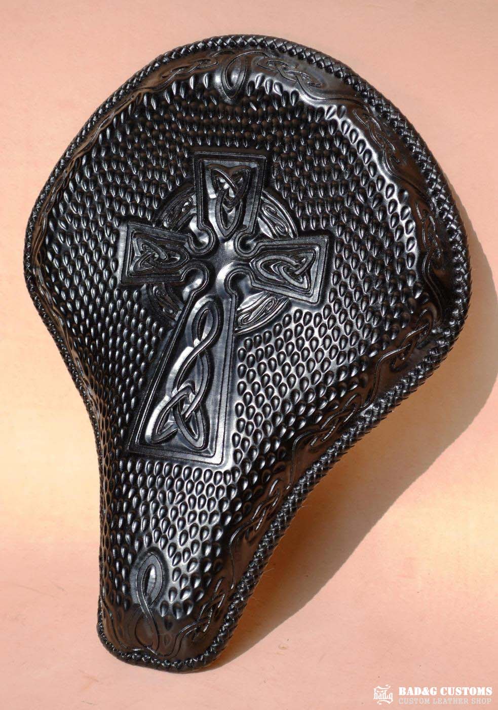"CROSS" design hand tooled and braided on a chopper solo seat. Black Veg tan leather with kangaroo lace.