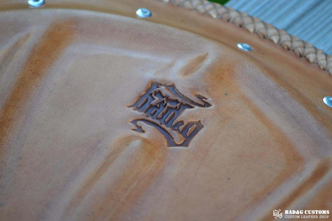 "CROSS" design hand tooled and braided on a chopper solo seat. Brown Veg tan leather with kangaroo lace.